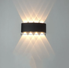 Modern wall-mounted light fixture casting a warm glow on a plain wall.