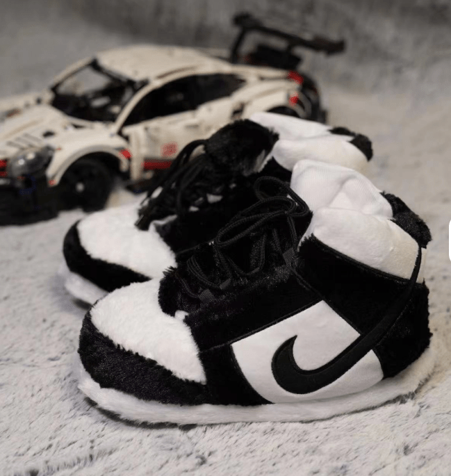 Black and white plush shoes with a prominent logo on a textured surface.