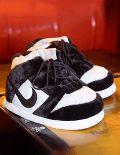 Black and white sneakers with fuzzy texture on a wooden surface.