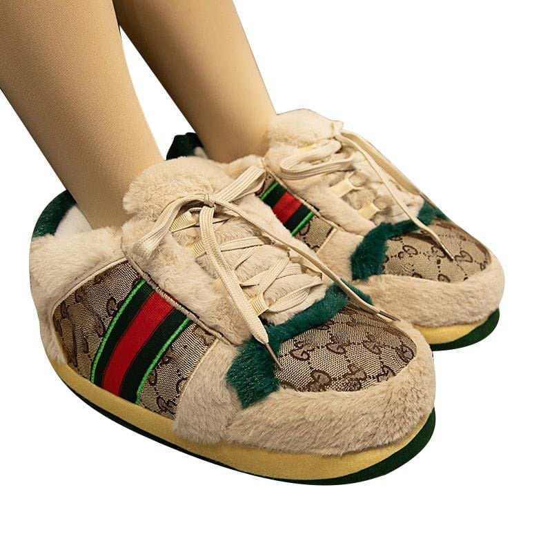 Beige slippers with patterned design and red and green stripes worn by a person on a white background