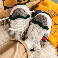 White sneakers with green and red accents on a fluffy surface with a yellow jacket in the background.